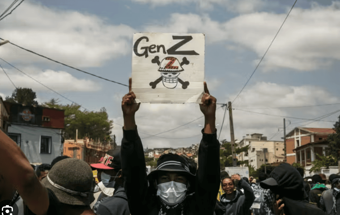 Un jeune manifestant brandit une pancarte indiquant son affiliation au mouvement qui mène la lutte. Antananarivo, Madagascar, 27:09:2025 ©AFP - Rijasolo